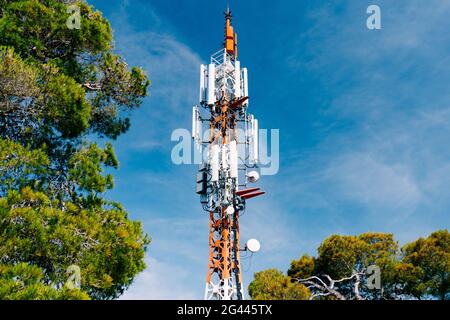 Zellenturm vor dem Hintergrund von grünen Bäumen und blauem Himmel. Nahaufnahme Stockfoto