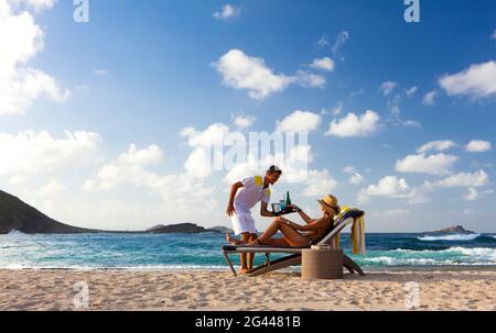 Strandservice. Am Strand wird die Frau vom Kellner bedient. St. Barths. Stockfoto