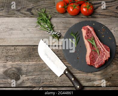 Frisches Stück Rindfleisch, Striploin-Steak auf einem schwarzen Brett mit Gewürzen Stockfoto