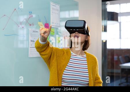 Asiatische Geschäftsfrau, die in Virtual Reality vor dem Whiteboard steht Headset Stockfoto