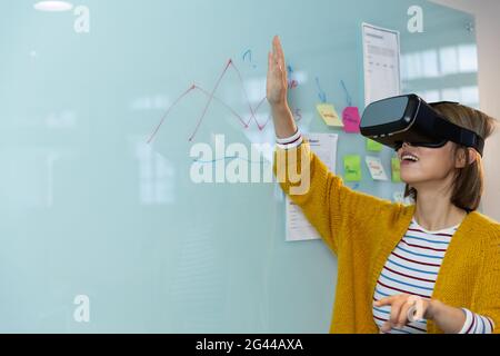 Porträt einer asiatischen Geschäftsfrau, die vor dem Whiteboard steht Virtual Reality-Headset Stockfoto