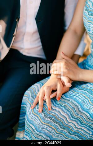 Mann in einem Anzug und Frau in einem gestreiften Blau Kleid sitzen und halten die Hände Stockfoto
