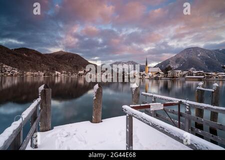 Blick über den winterlichen Tegernsee auf das Dorf Rottach-Egern mit der Kirche Sankt Laurentius, Bayern, Deutschland. Stockfoto