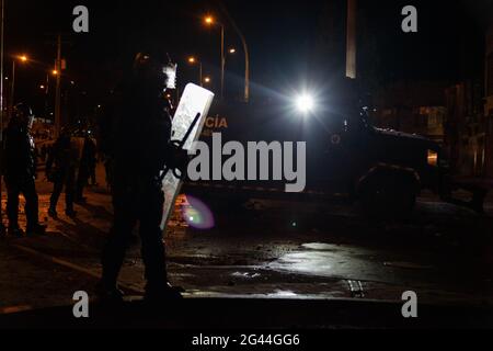Bogota, Kolumbien. Juni 2021. Der kolumbianische Bereitschaftspolizist wird von einem Flutlicht eines gepanzerten Lastwagens beleuchtet, als in der Nacht des 17. Juni 2021 in Bogota, Kolumbien, die Zusammenstöße zwischen Demonstranten und der kolumbianischen Bereitschaftspolizei (ESMAD) eskalierten, während regierungsfeindliche Proteste gegen die Polizeibrutalität und die Regierung von Präsident Ivan Duque stattfanden. Kredit: Long Visual Press/Alamy Live Nachrichten Stockfoto
