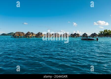 Kleines Motorboot in der Bora Bora Lagune mit Überwasser-Bungalows im Bora Bora Pearl Beach Resort, Bora Bora, Leeward Islands, Französisch-Polynesien, so Stockfoto