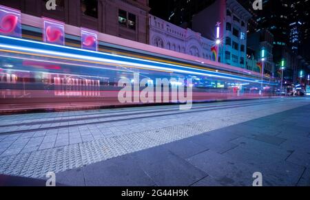 Die Straßenbahn fährt nachts durch die George Street und hinterlässt farbenfrohe Lichtwege in Sydney, NSW, Australien Stockfoto