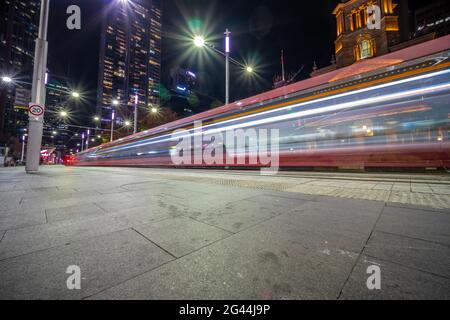 Die Straßenbahn fährt nachts durch die George Street und hinterlässt farbenfrohe Lichtwege in Sydney, NSW, Australien Stockfoto