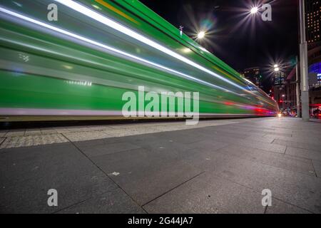 Die Straßenbahn fährt nachts durch die George Street und hinterlässt farbenfrohe Lichtwege in Sydney, NSW, Australien Stockfoto