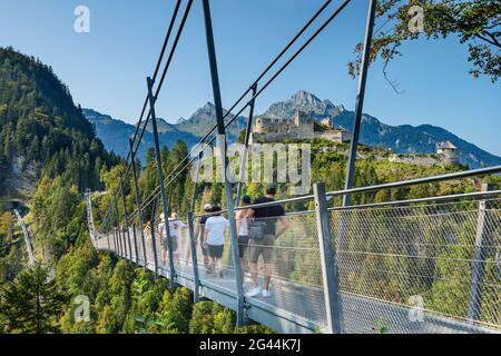 Mehrere Menschen laufen über die Seilbrücke Highline 179 mit der Burgruine Ehrenberg im Hintergrund, Reutte, Tirol, Österreich Stockfoto