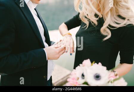 Der Mann legt einen Verlobungsring auf den Finger einer Frau Nachdem sie seinen Vorschlag akzeptiert hat Stockfoto