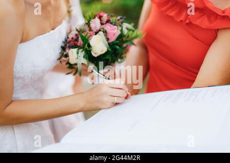 Die Braut unterschreibt die Hochzeitsurkunde während der Hochzeitszeremonie aus nächster Nähe. Stockfoto