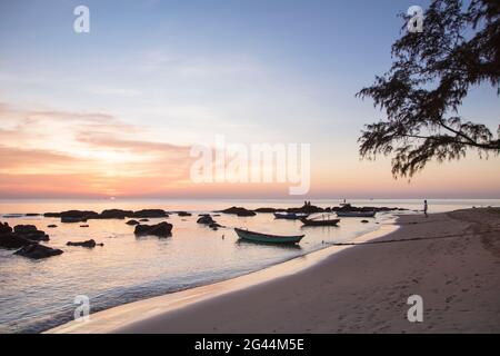 Silhouette von Felsen und Fischerbooten am Ong lang Beach bei Sonnenuntergang, Ong lang, Phu Quoc Island, Kien Giang, Vietnam, Asien Stockfoto
