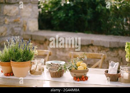 Empfang am Tisch für Hochzeitsessen bei Sonnenuntergang im Freien. Alte rechteckige Holztische mit Lappen Läufer, Holz Vintage Stühle, Lave Stockfoto