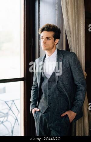 Der Bräutigam lehnte sich an den Rahmen des großen Fensters der alten Villa. Comer See Stockfoto