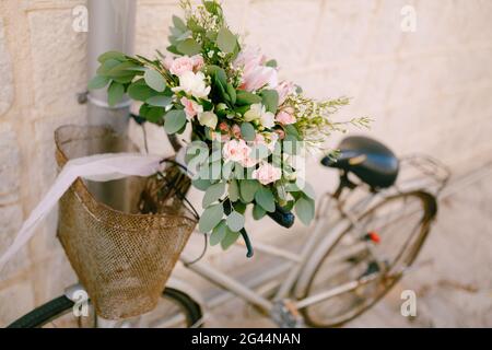 Brautstrauß aus rosa Rosen, Ästen von Eukalyptusbäumen, Capsella und weißen Bändern auf dem Fahrrad Stockfoto