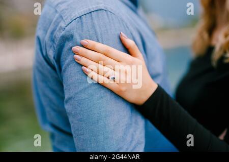 Das Mädchen legte ihre Hand mit einem Ring auf die Schulter des Mannes. Nahaufnahme Stockfoto