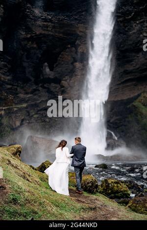 Destination Island Hochzeit, in der Nähe des Kvernufoss Wasserfalls. Hochzeitspaar geht zum Wasserfall. Stockfoto