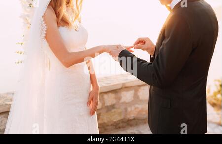 Der Bräutigam legt den Ring während der Hochzeit auf den Finger der Braut Die Hochzeitszeremonie Stockfoto