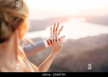 Die Braut und der Bräutigam stehen auf dem Berg Lovcen mit Blick auf die Bucht von Kotor, die Braut legt ihre Hand auf die Hand des Bräutigams Stockfoto