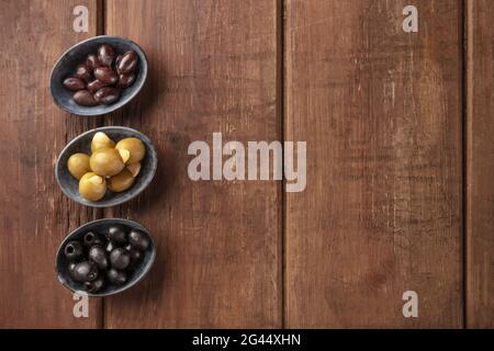 Verschiedene Oliven in Schalen, von oben auf einem rustikalen Holzhintergrund mit Kopierfläche geschossen Stockfoto