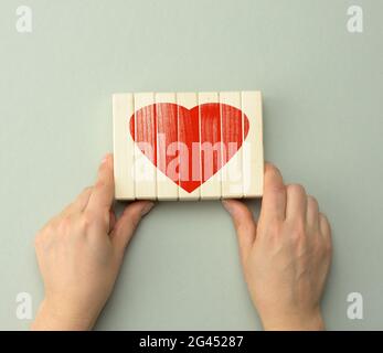 Gesammelt rotes Herz auf Holzbalken von zwei Händen gehalten. Konzept von Liebe, Freundschaft Stockfoto