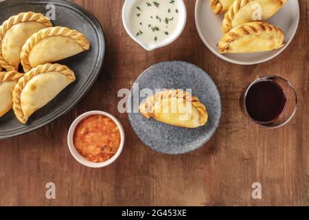 Empanadas mit Saucen und Wein, Schuß von der Oberseite in einem dunklen Holzmöbeln im Landhausstil Hintergrund Stockfoto