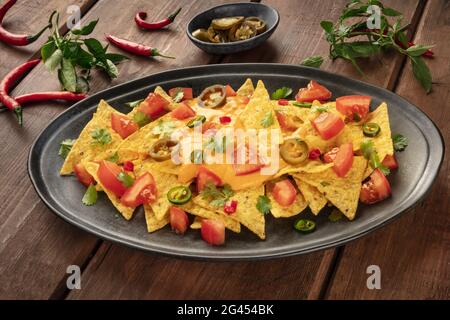 Mexikanische Nachos mit einer Käsesauce, Chili und Jalapeno Paprika, Tomaten. Und Koriander Stockfoto