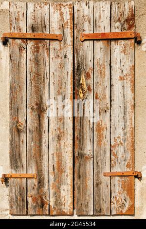 Nahaufnahme eines Fensters mit geschlossenen alten Fensterläden mit rostigen Verbindungselementen. Stockfoto