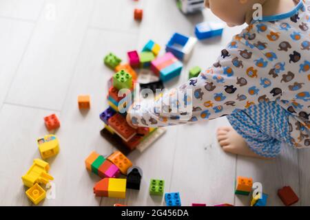 Junge Kind spielt mit seiner Mutter in Farbe Kinder-Baukasten. Die Details des Kinderbaukastens sind auf dem Boden verstreut. Stockfoto