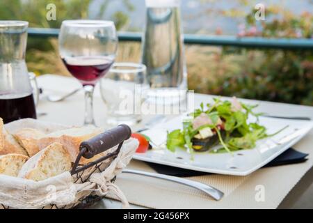 Karaffe Rotwein mit zwei Gläsern auf dem Tisch mit Essgeschirr. Stockfoto