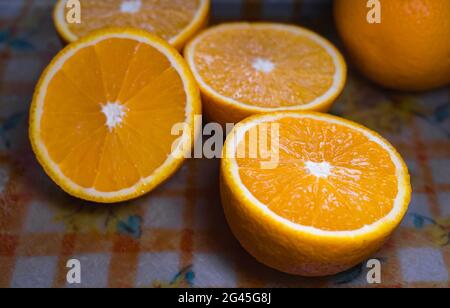 Selektiver Fokus von ein paar Orangen in zwei Hälften geschnitten und auf einem Kunststoff-Schneidebrett platziert. Stockfoto