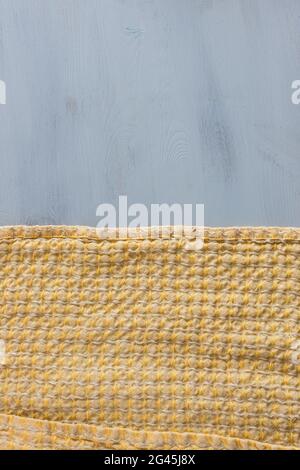 Orangefarbenes und gelbes warmes Tuch und quadratisches Muster über einem grauen Holztisch. Stockfoto