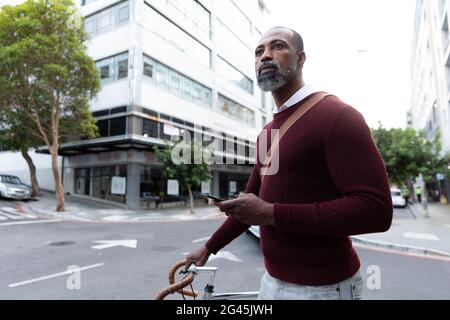 Afroamerikanischer Mann hält sein Fahrrad in der Straße der Stadt Stockfoto