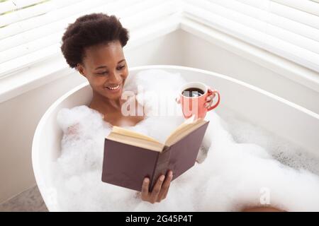 Frau mit Kaffeetasse Lesebuch in einer Badewanne Stockfoto