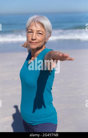 Ältere kaukasische Frau, die am Strand Yoga praktiziert. Stockfoto