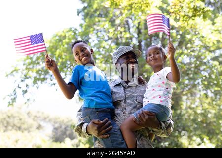 Afroamerikanischer Mann in Militäruniform, der seine Kinder hält Stockfoto