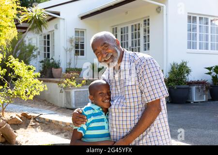 Ein älterer afroamerikanischer Mann und sein Enkel verbringen an einem sonnigen Tag Zeit zusammen in ihrem Garten Stockfoto