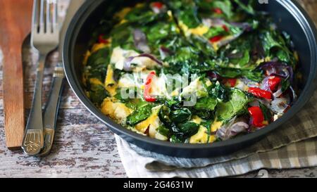 Gesundes hausgemachtes Omelett mit Spinat und Gemüse. Spinat-Omelett in einer Pfanne. Kochen gesunde Lebensmittel zu Hause. Stockfoto