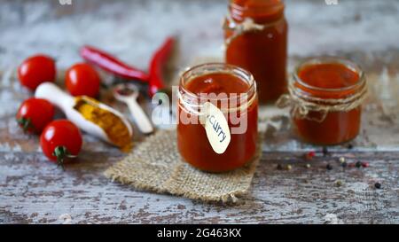 Hausgemachte Curry-Sauce. Gläser mit Sauce, Tomaten, Gewürzen. Stockfoto