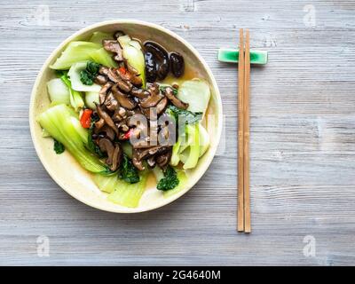 chinesische Küche - Draufsicht auf Bok Choy Kohl mit aromatischen Shiitake-Pilzen in Keramikschale auf Holztisch Stockfoto