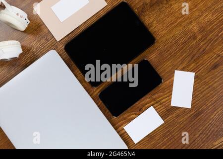 Blick auf einen Laptop mit Tablet und Smartphone, eine Kuverppe Und Papiere auf Holztisch Hintergrund Stockfoto