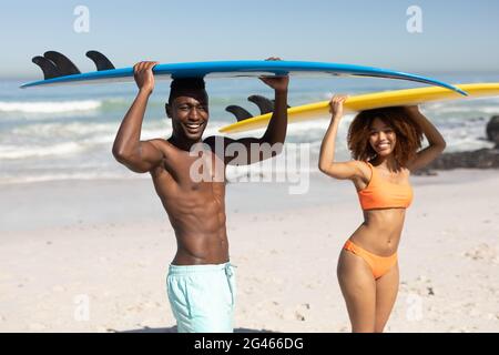 Gemischtes Rennpaar hält Surfbretter am Strand Stockfoto