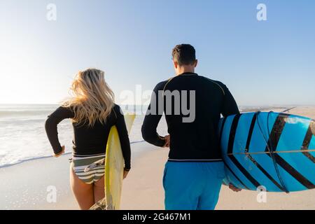 Kaukasisches Paar hält Surfbretter am Strand. Stockfoto
