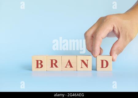 Markenbildung Erfolg im Geschäftskonzept. Handstapelbare Holzblöcke mit Wortmarke auf blauem Hintergrund. Stockfoto