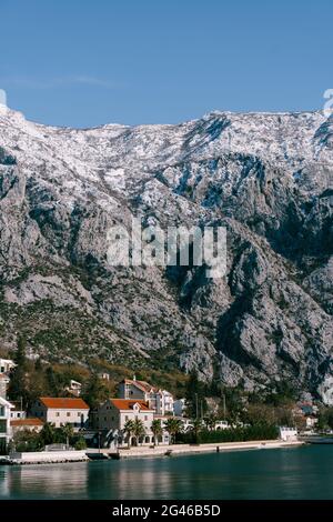 Felsige schneebedeckte Berge über Häusern im Golf von Kotor, Montenegro. Stockfoto