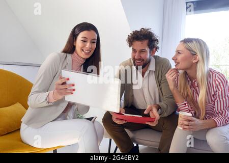 Eine Gruppe junger Geschäftsleute ist gut gelaunt, wenn sie von zu Hause aus in entspannter Atmosphäre arbeiten. Menschen, Geschäfte, Meetings Stockfoto