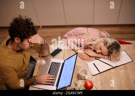 Junges kaukasisches Paar, das spät in der Nacht von zu Hause aus arbeitet. Burnout, Lockdown-Konzept Stockfoto