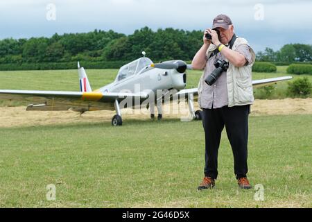 Turweston Airfield, Buckinghamshire, Großbritannien - Samstag, 19. Juni 2021 - Piloten und Luftfahrtbegeisterte haben heute an einem bewölkten Sommertag die Möglichkeit, am Air Britain Fly-in auf dem Turweston Airfield teilzunehmen. Das Foto zeigt einen Luftfahrtenthusiasten, der im Hintergrund ein DHC 1 Chipmunk-Flugzeug fotografiert. Foto Steven May / Alamy Live News Stockfoto