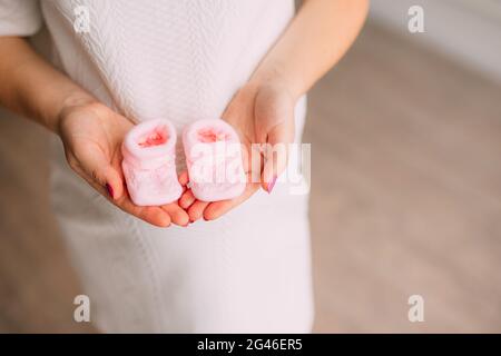 Baby Booties in den Händen der schwangeren Mutter Stockfoto