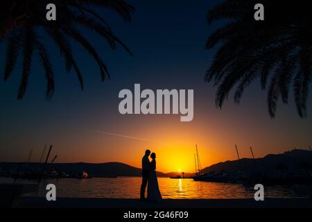Silhouette von einem Brautpaar auf dem Hintergrund der untergehenden Sonne Stockfoto